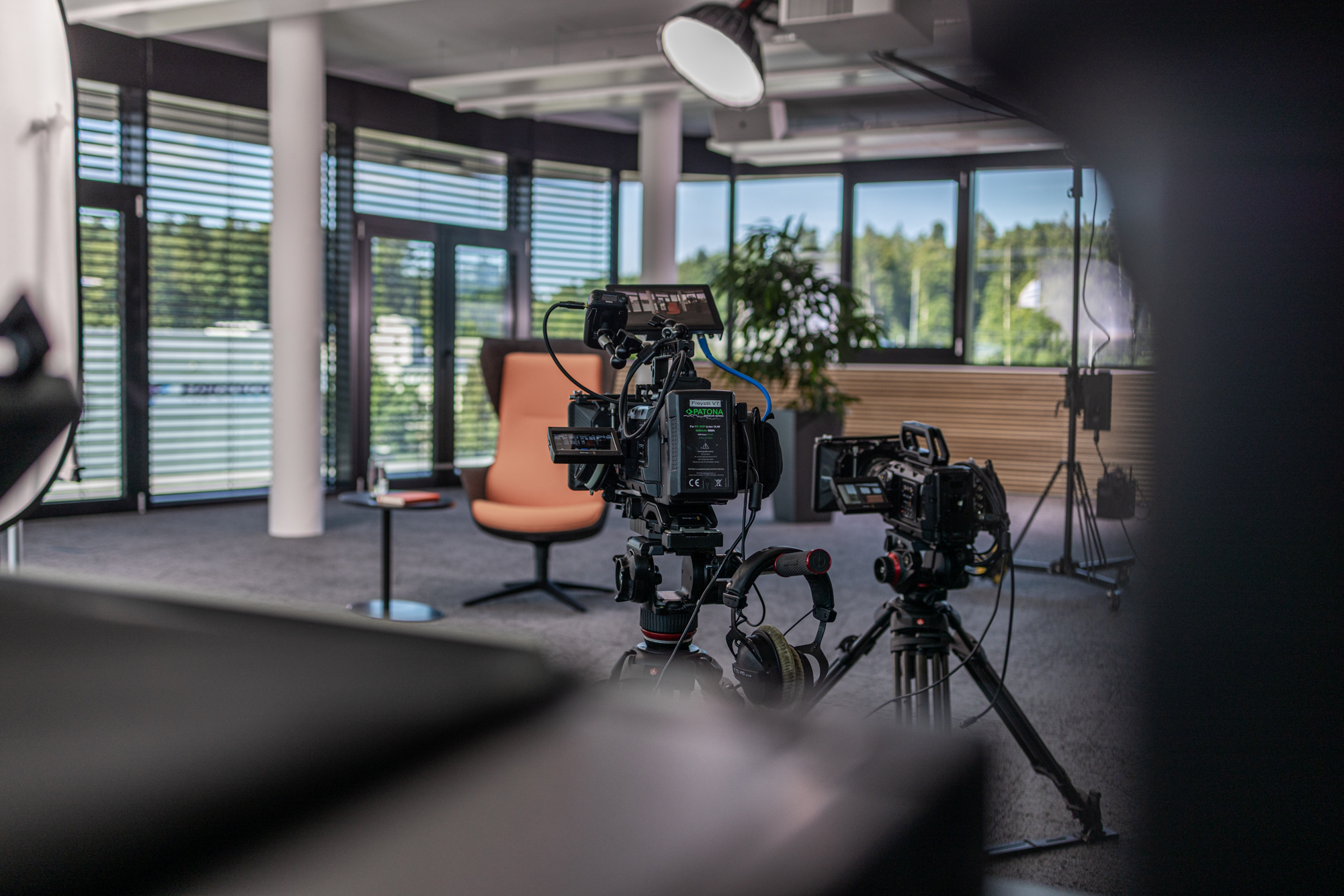 Zwei professionelle Videokameras auf Stativen in einem modernen, hellen Aufnahmestudio.